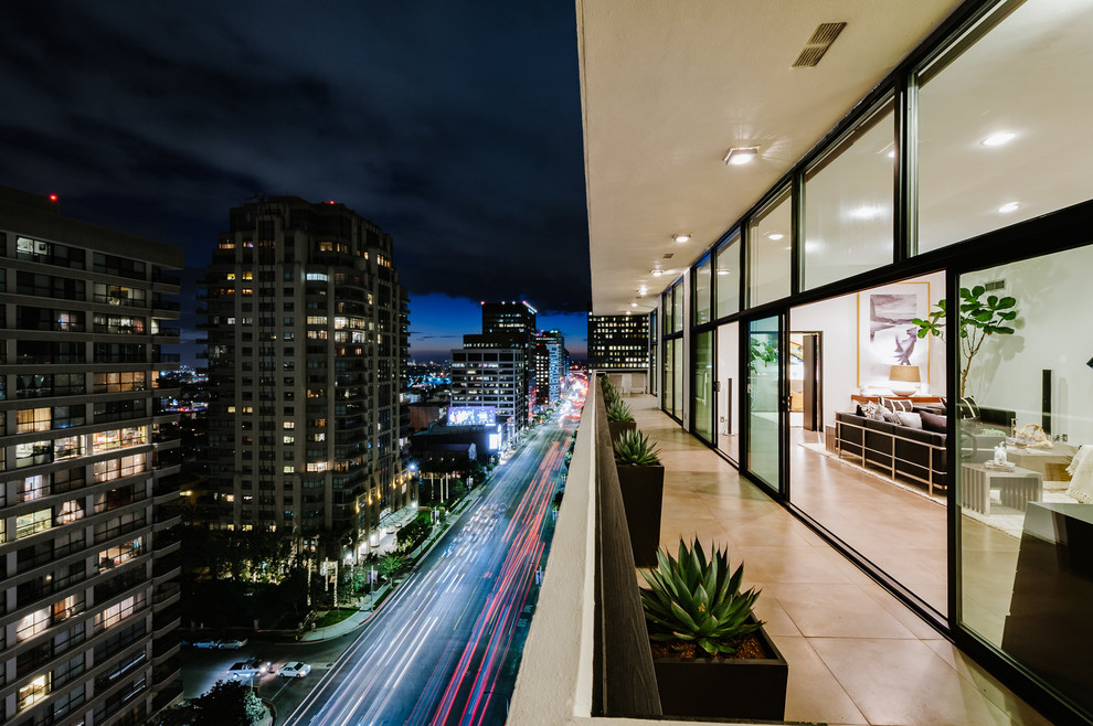 Photo of an expansive modern balcony in Los Angeles with a roof extension and mixed railing.