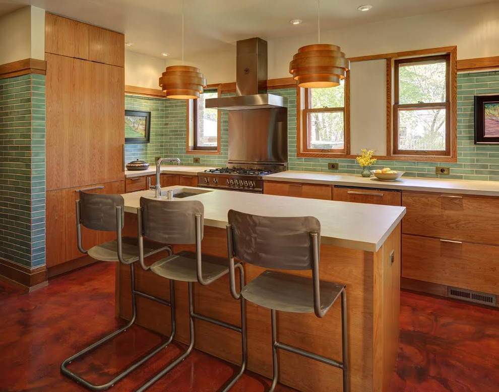 This is an example of a mid-sized midcentury l-shaped eat-in kitchen in Milwaukee with a farmhouse sink, flat-panel cabinets, medium wood cabinets, green splashback, ceramic splashback, stainless steel appliances, with island, solid surface benchtops, vinyl floors and brown floor.