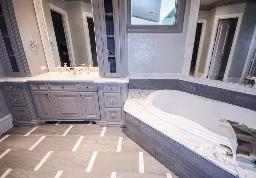 Photo of a large transitional master bathroom in Houston with grey cabinets, marble benchtops, a corner tub, a corner shower, a bidet and gray tile.