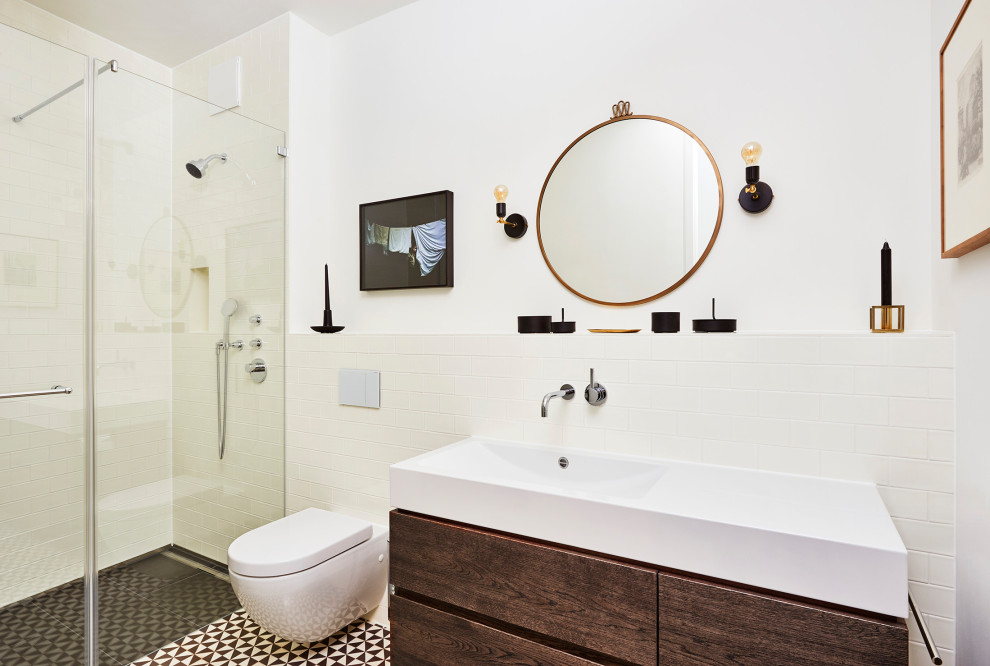 Bild på ett litet funkis badrum, med möbel-liknande, vita skåp, en hörndusch, en vägghängd toalettstol, beige kakel, beige väggar, cementgolv, svart golv och dusch med gångjärnsdörr