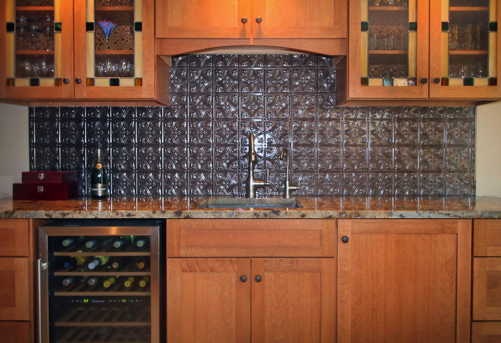This is an example of a mid-sized traditional single-wall wet bar in Chicago with an undermount sink, shaker cabinets, medium wood cabinets, granite benchtops, brown splashback, metal splashback and carpet.