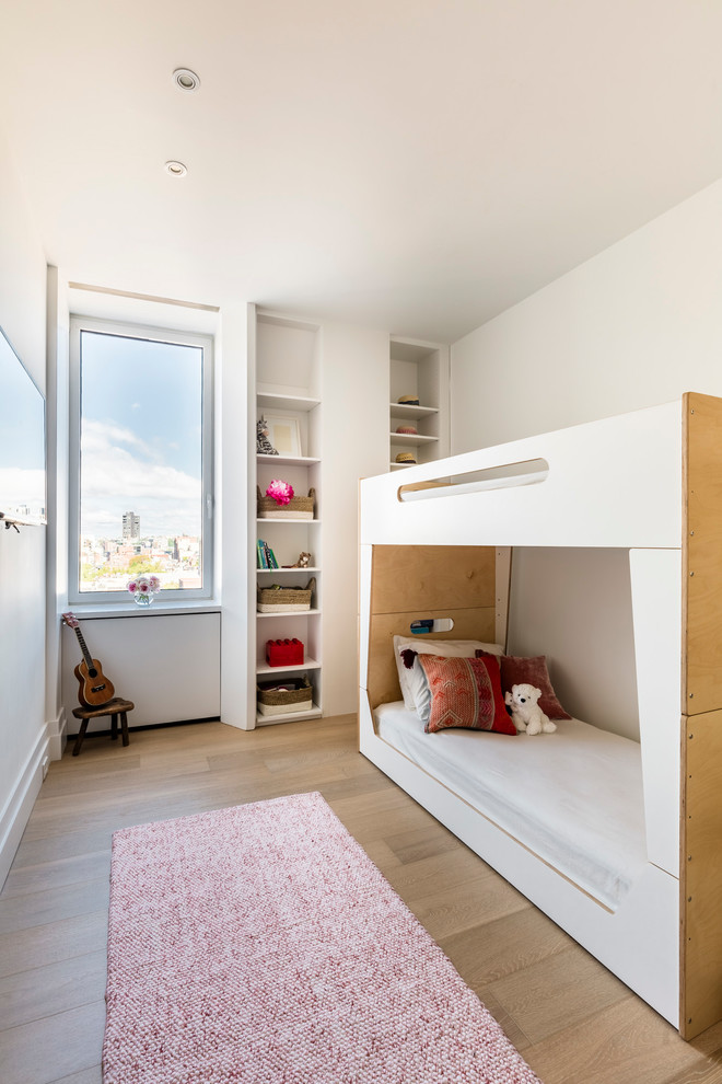 This is an example of a contemporary gender-neutral kids' bedroom in New York with white walls, light hardwood floors and brown floor.