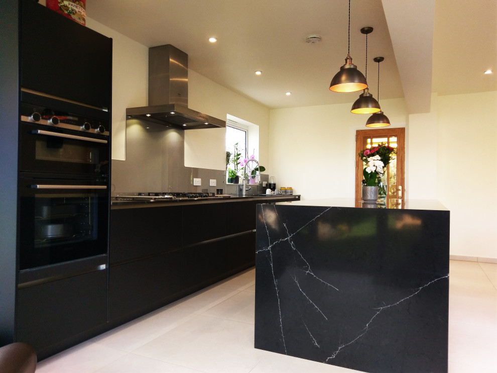 Inspiration for a large traditional galley eat-in kitchen in London with a single-bowl sink, shaker cabinets, black cabinets, granite benchtops, black splashback, marble splashback, black appliances, marble floors, with island, beige floor, black benchtop and wood.