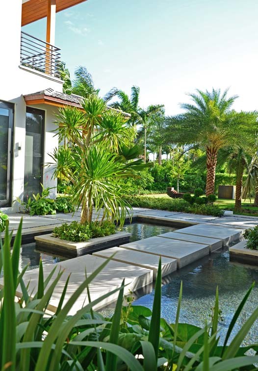 Photo of a large asian front yard full sun driveway in Miami with natural stone pavers.