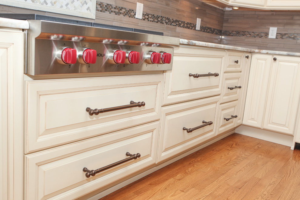 Example of a large transitional u-shaped light wood floor eat-in kitchen design in Newark with an undermount sink, raised-panel cabinets, distressed cabinets, granite countertops, brown backsplash, mosaic tile backsplash, stainless steel appliances and an island