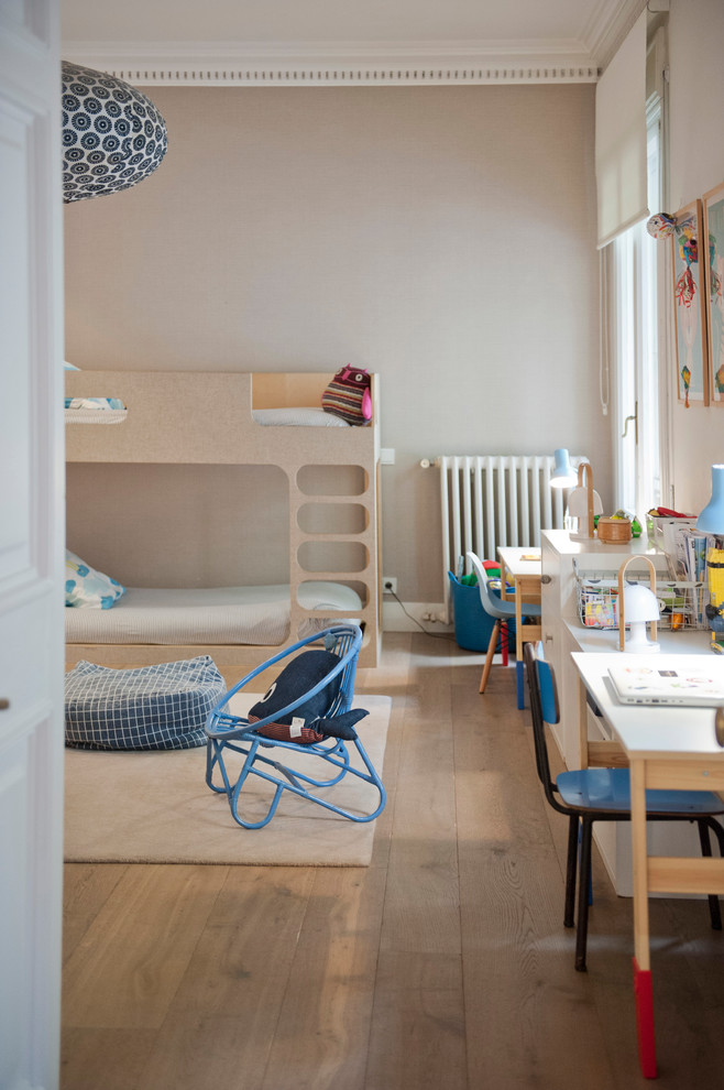 Design ideas for a mid-sized transitional gender-neutral kids' bedroom for kids 4-10 years old in Barcelona with beige walls and medium hardwood floors.