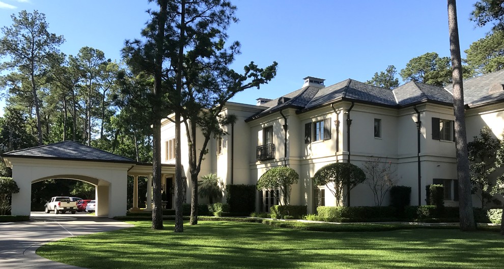Large transitional two-storey stucco white house exterior in Houston with a hip roof and a shingle roof.