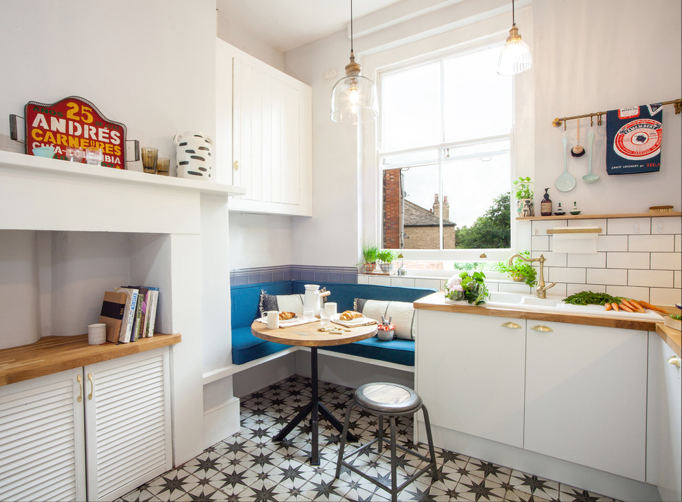 Small eclectic eat-in kitchen in London with a double-bowl sink, flat-panel cabinets, white cabinets, wood benchtops, subway tile splashback, panelled appliances, ceramic floors, no island and multi-coloured floor.