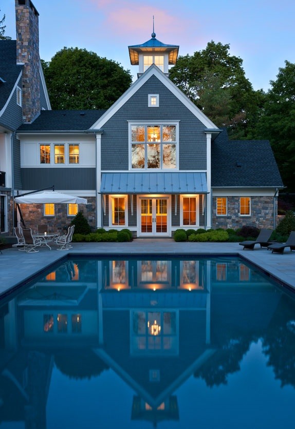 Design ideas for an expansive transitional courtyard rectangular lap pool in Boston with a pool house and natural stone pavers.