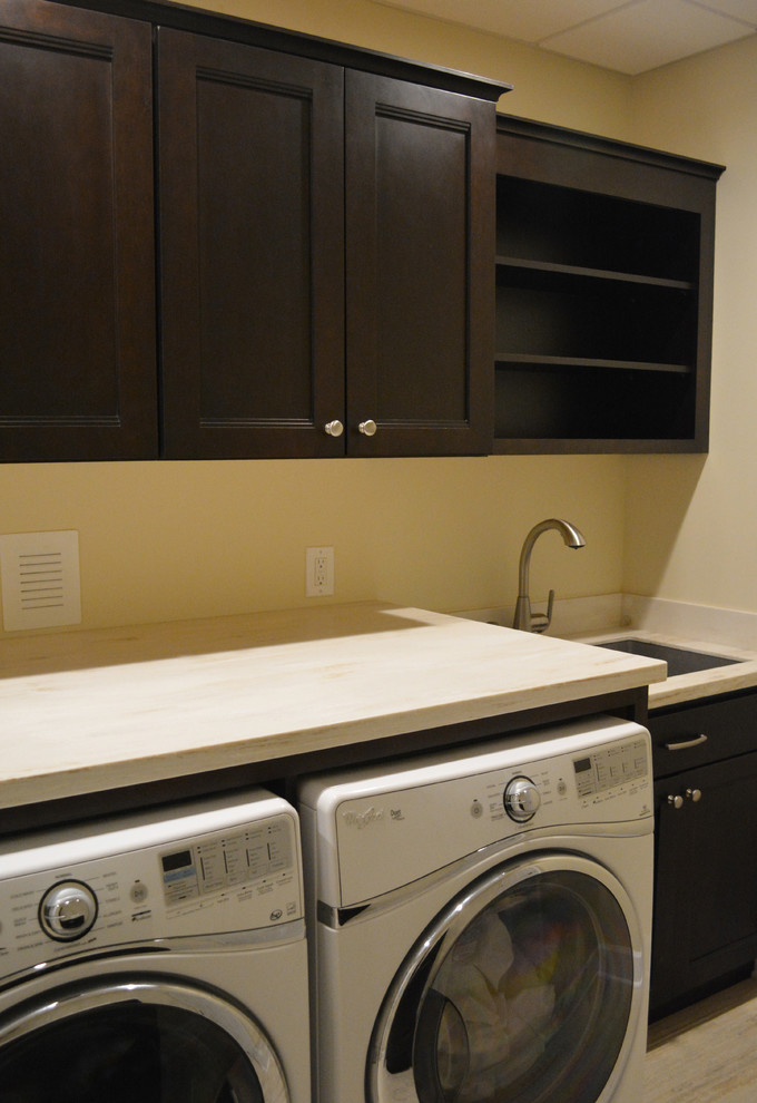 Design ideas for a small transitional single-wall dedicated laundry room in Philadelphia with recessed-panel cabinets, dark wood cabinets, an undermount sink, yellow walls and a side-by-side washer and dryer.