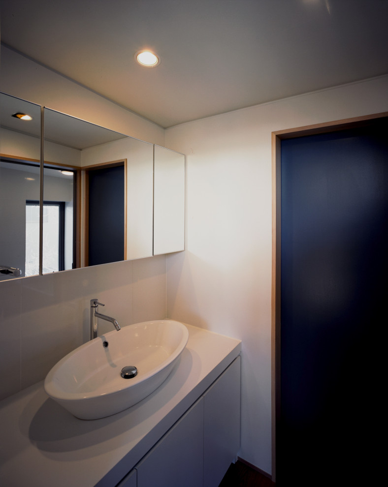 Exempel på ett modernt vit vitt toalett, med luckor med profilerade fronter, vita skåp, vit kakel, vita väggar, mellanmörkt trägolv, ett fristående handfat och bänkskiva i akrylsten
