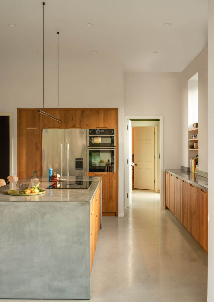 Photo of a large country l-shaped eat-in kitchen in Other with flat-panel cabinets, medium wood cabinets, concrete benchtops, with island and grey benchtop.