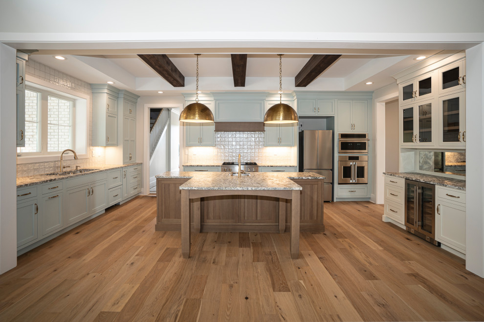 Exempel på ett stort klassiskt flerfärgad flerfärgat kök, med en undermonterad diskho, luckor med profilerade fronter, blå skåp, granitbänkskiva, vitt stänkskydd, stänkskydd i porslinskakel, rostfria vitvaror, ljust trägolv, en köksö och brunt golv