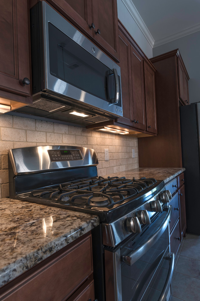 Open concept kitchen - mid-sized transitional l-shaped travertine floor open concept kitchen idea with an undermount sink, shaker cabinets, medium tone wood cabinets, granite countertops, beige backsplash, stone tile backsplash, stainless steel appliances and an island