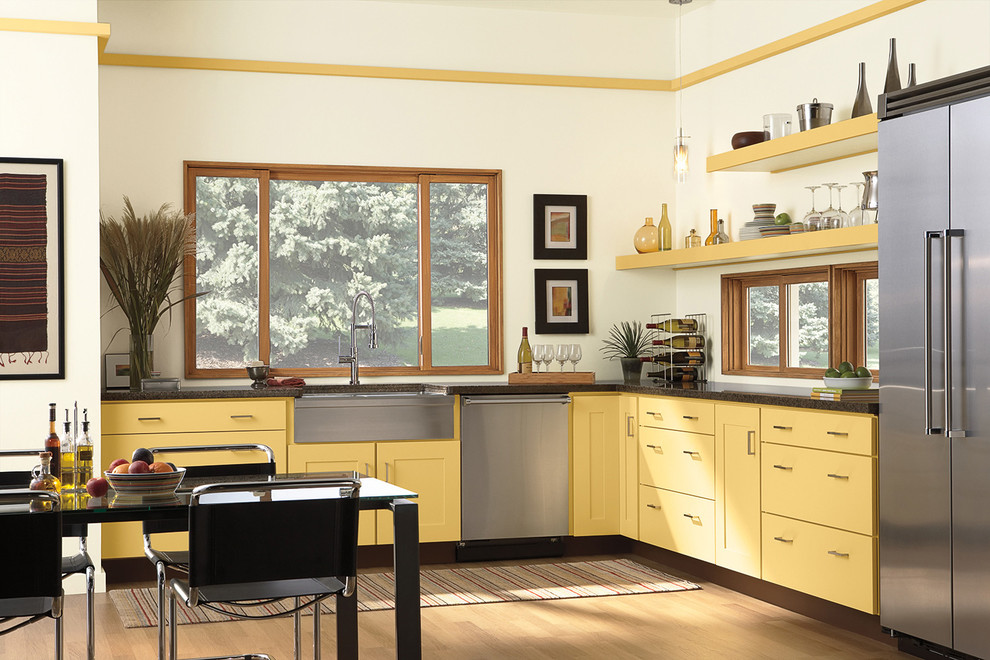 Inspiration for a mid-sized contemporary l-shaped light wood floor and brown floor eat-in kitchen remodel in Chicago with a farmhouse sink, flat-panel cabinets, light wood cabinets, granite countertops, stainless steel appliances, no island and black countertops