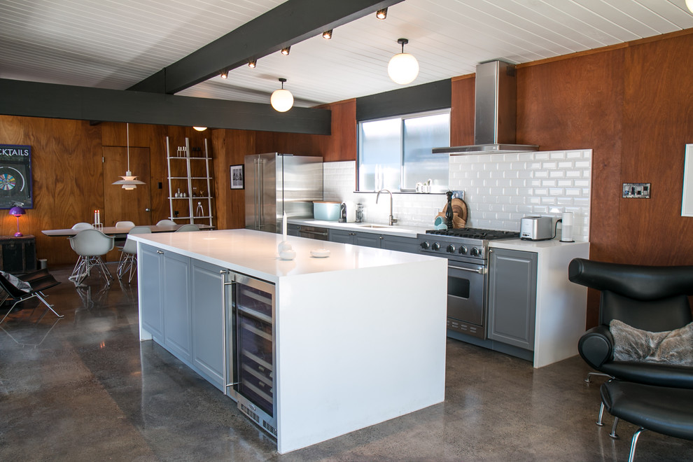 Mid-sized midcentury single-wall eat-in kitchen in San Francisco with an integrated sink, recessed-panel cabinets, grey cabinets, quartzite benchtops, white splashback, ceramic splashback, stainless steel appliances, concrete floors and with island.