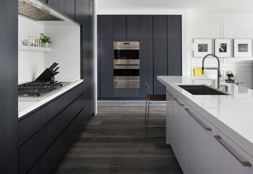Photo of a mid-sized contemporary l-shaped eat-in kitchen in Minneapolis with flat-panel cabinets, with island, an undermount sink, black cabinets, quartzite benchtops, panelled appliances, medium hardwood floors and grey floor.