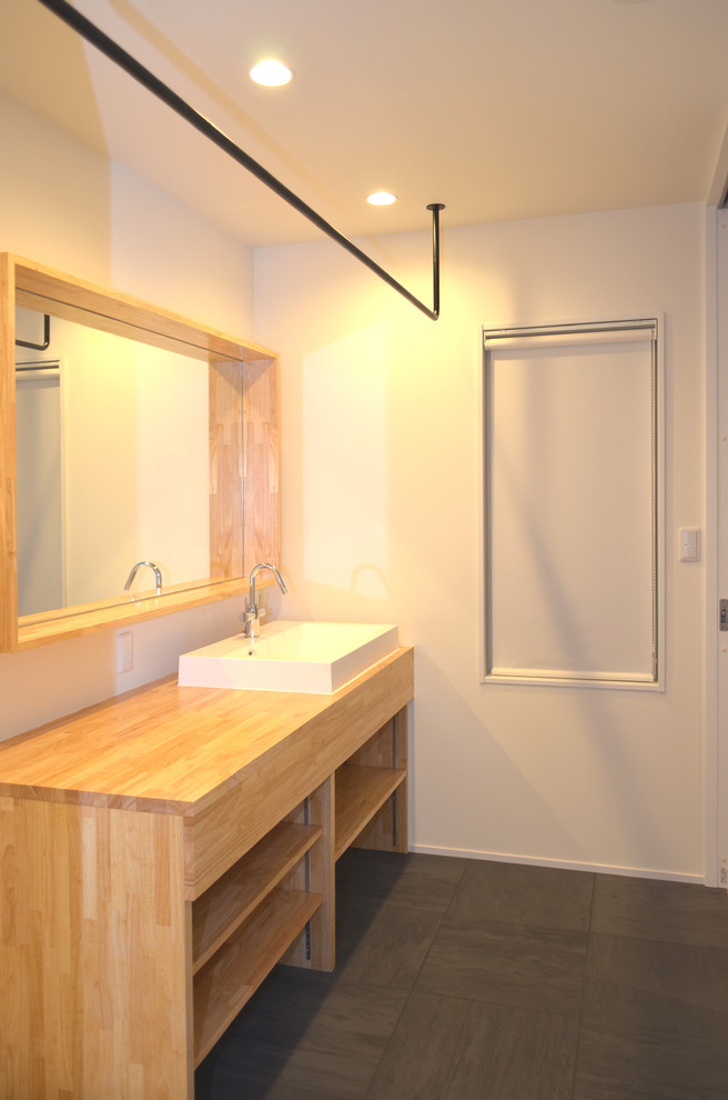 Small scandinavian single-wall dedicated laundry room in Other with a drop-in sink, open cabinets, wood benchtops, white walls, linoleum floors, an integrated washer and dryer, black floor and beige benchtop.