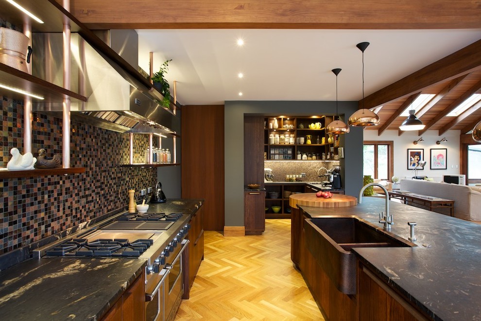 Large contemporary galley eat-in kitchen in Auckland with a farmhouse sink, flat-panel cabinets, medium wood cabinets, granite benchtops, multi-coloured splashback, mosaic tile splashback, stainless steel appliances, light hardwood floors and with island.