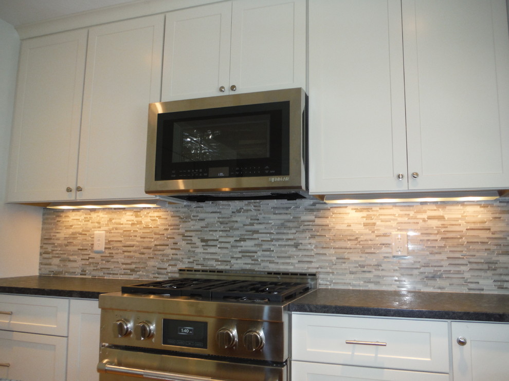 Kitchen - transitional kitchen idea in Boston with shaker cabinets, white cabinets, granite countertops, beige backsplash, mosaic tile backsplash and stainless steel appliances