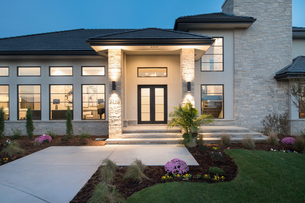 Photo of a large contemporary two-storey stucco beige exterior in Wichita with a hip roof.