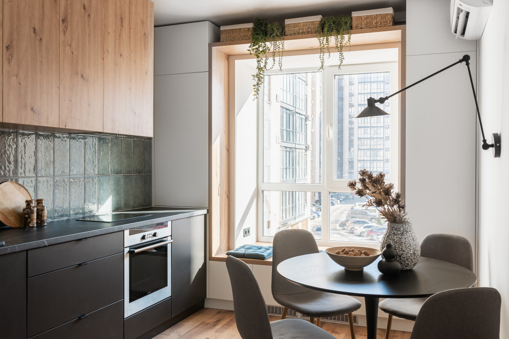 Photo of a mid-sized contemporary u-shaped eat-in kitchen in Other with a drop-in sink, flat-panel cabinets, black cabinets, laminate benchtops, blue splashback, ceramic splashback, stainless steel appliances, laminate floors, no island and black benchtop.