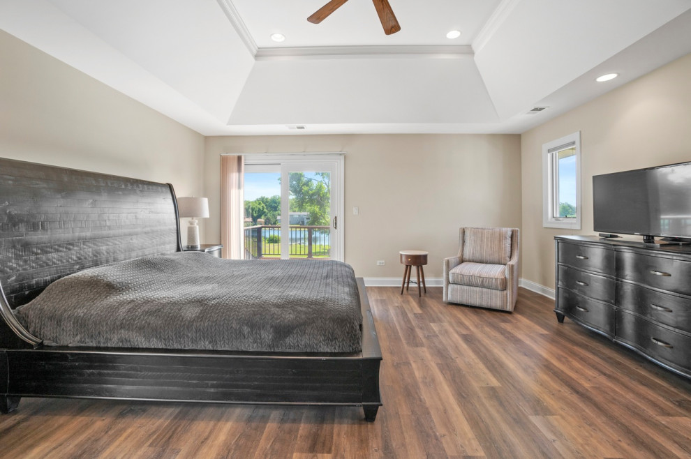 This is an example of a large transitional master bedroom in Chicago with beige walls, light hardwood floors, no fireplace, brown floor, recessed and decorative wall panelling.