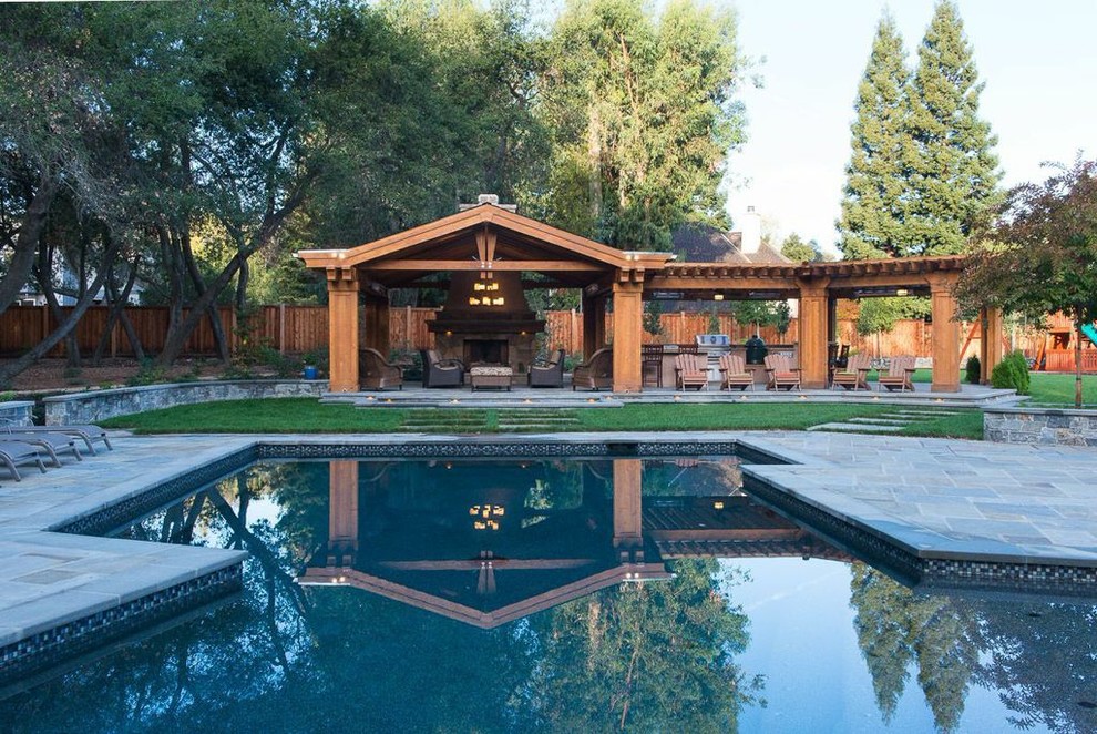 This is an example of an expansive arts and crafts backyard custom-shaped lap pool in San Francisco with natural stone pavers.