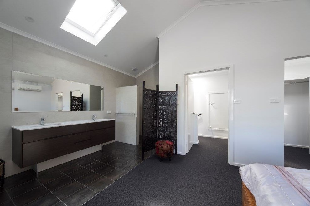 Photo of a large contemporary master bathroom in Canberra - Queanbeyan with flat-panel cabinets, dark wood cabinets, an open shower, a two-piece toilet, beige tile, travertine, white walls, travertine floors, an integrated sink, black floor and an open shower.