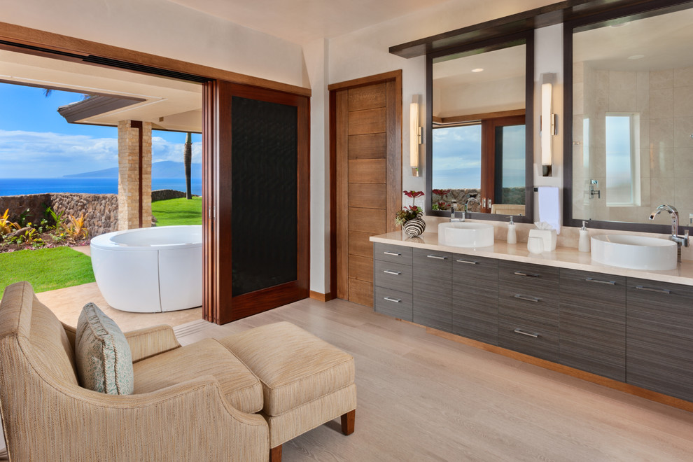 Photo of a large contemporary master wet room bathroom in Hawaii with flat-panel cabinets, a hot tub, a vessel sink, beige floor, dark wood cabinets, porcelain floors, white walls and limestone benchtops.