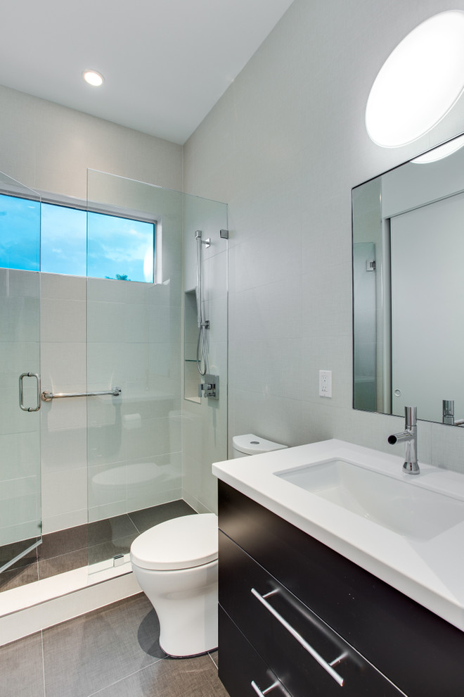 Small contemporary kids bathroom in Tampa with an undermount sink, flat-panel cabinets, black cabinets, engineered quartz benchtops, a two-piece toilet, white tile, porcelain tile, white walls and porcelain floors.