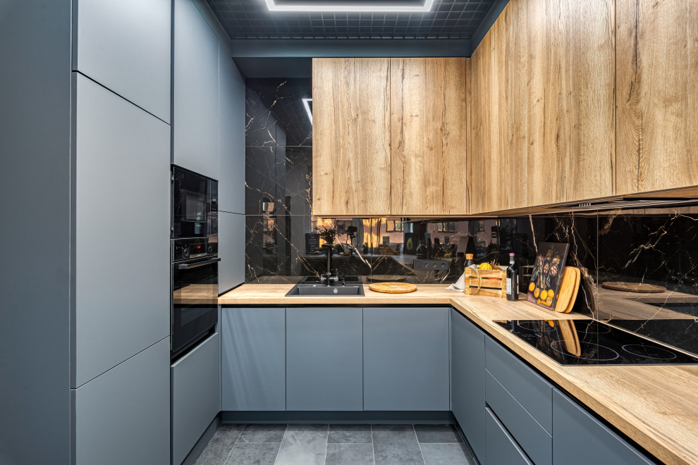Design ideas for a mid-sized industrial galley separate kitchen in Moscow with an undermount sink, flat-panel cabinets, black cabinets, wood benchtops, black splashback, porcelain splashback, black appliances, marble floors, with island and brown benchtop.