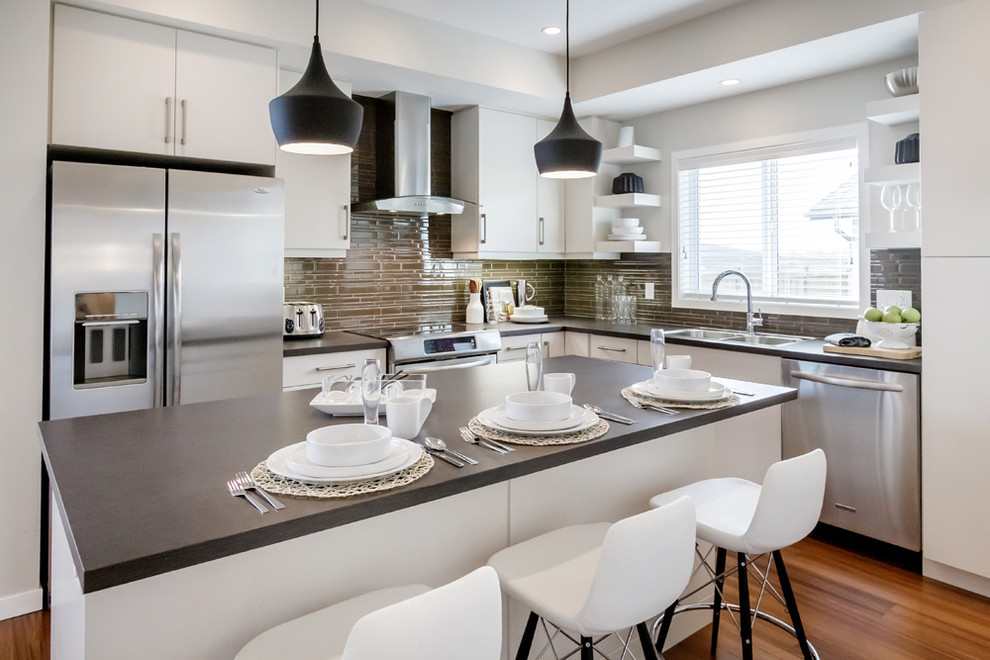 Inspiration for a modern l-shaped kitchen in Calgary with flat-panel cabinets, white cabinets, stainless steel appliances, a drop-in sink and green splashback.