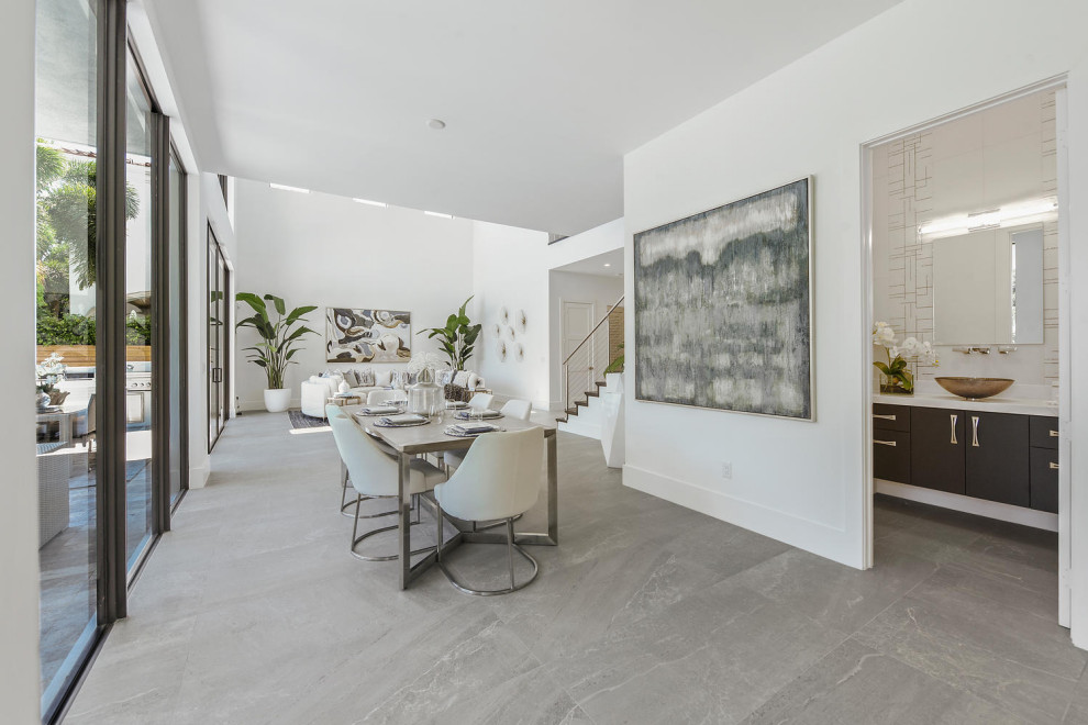 Ispirazione per una sala da pranzo aperta verso la cucina minimalista con pareti bianche, pavimento in gres porcellanato e pavimento beige