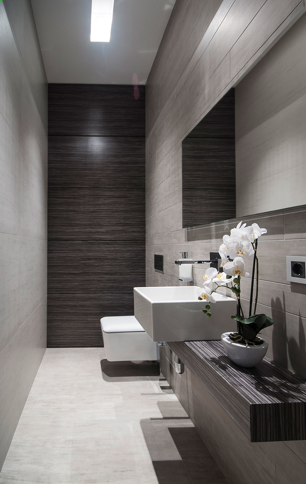 Photo of a contemporary powder room in Moscow with a wall-mount toilet, gray tile and a vessel sink.