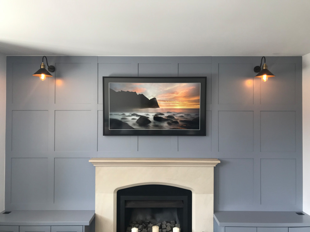 オークランドにある低価格の中くらいなトラディショナルスタイルのおしゃれな独立型ファミリールーム (青い壁、標準型暖炉、コンクリートの暖炉まわり、壁掛け型テレビ、パネル壁) の写真