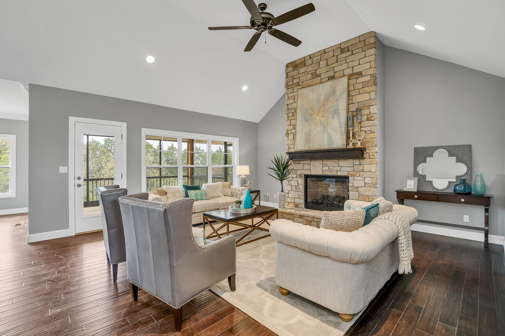 Design ideas for a mid-sized transitional open concept family room in St Louis with medium hardwood floors, a stone fireplace surround, grey walls, a standard fireplace, no tv and brown floor.