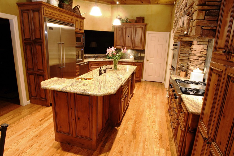 Example of a mountain style eat-in kitchen design in St Louis with an undermount sink, raised-panel cabinets, medium tone wood cabinets, granite countertops and stainless steel appliances