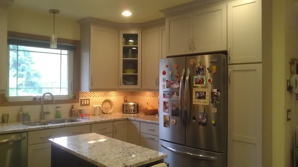 Mid-sized transitional u-shaped vinyl floor home design photo with an undermount sink, shaker cabinets, white cabinets, granite countertops, white backsplash, subway tile backsplash, stainless steel appliances and an island