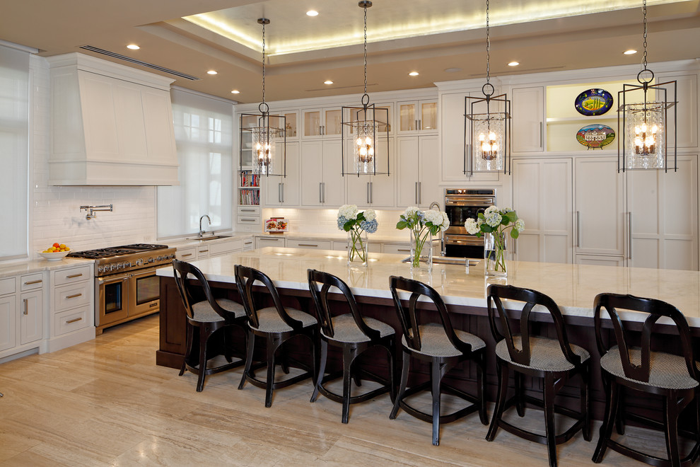 This is an example of a large transitional u-shaped open plan kitchen in Orlando with an undermount sink, shaker cabinets, white cabinets, quartz benchtops, white splashback, ceramic splashback, panelled appliances, marble floors, with island and beige floor.
