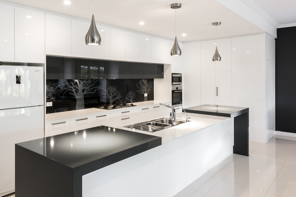 Photo of a mid-sized contemporary l-shaped kitchen pantry in Adelaide with a double-bowl sink, flat-panel cabinets, white cabinets, quartz benchtops, black splashback, glass sheet splashback, stainless steel appliances, ceramic floors and with island.