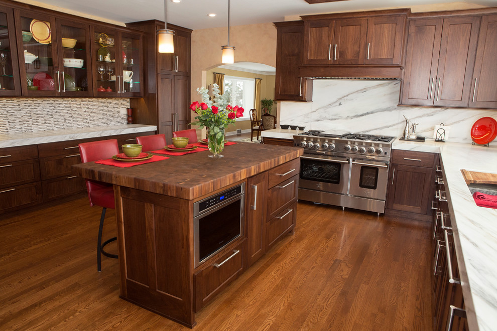 Enclosed kitchen - huge transitional l-shaped medium tone wood floor enclosed kitchen idea in Chicago with an undermount sink, flat-panel cabinets, medium tone wood cabinets, marble countertops, white backsplash, stone slab backsplash, stainless steel appliances and an island