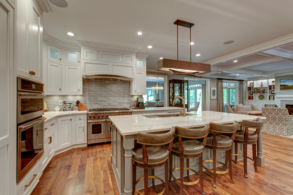 Photo of a large transitional u-shaped open plan kitchen in Raleigh with beaded inset cabinets, white cabinets, grey splashback, dark hardwood floors, with island, stainless steel appliances, marble benchtops and subway tile splashback.