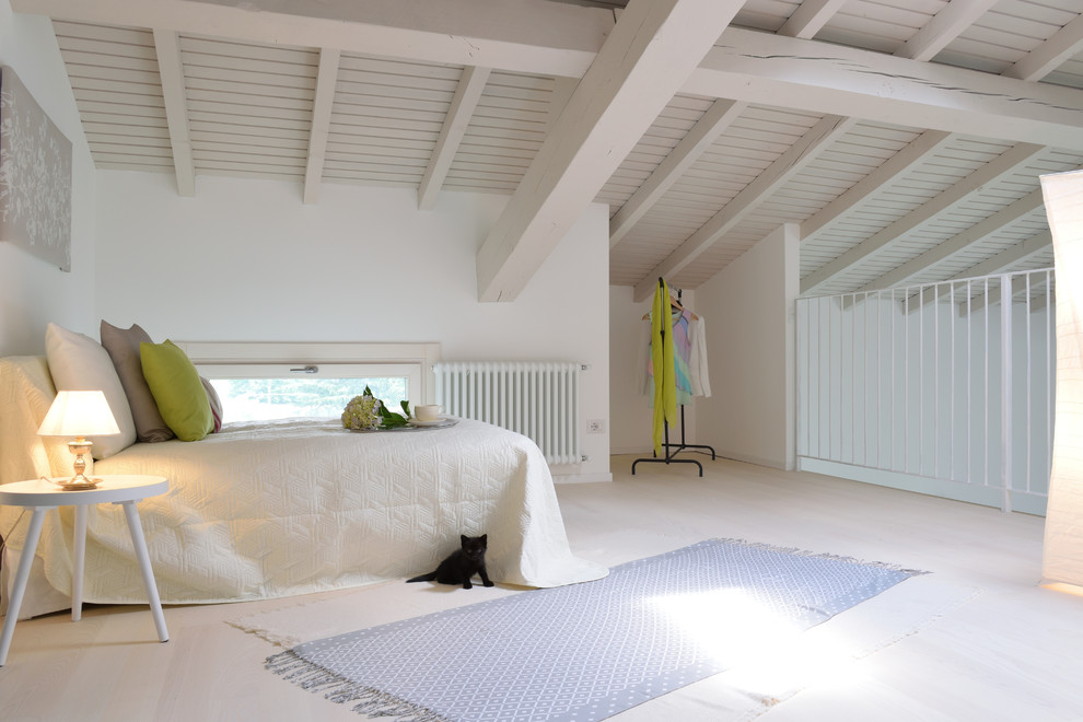 This is an example of a mediterranean loft-style bedroom in Milan with white walls, light hardwood floors and beige floor.