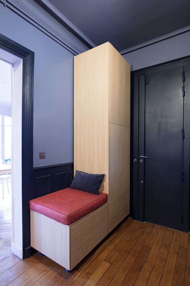 This is an example of a small contemporary foyer in Paris with blue walls and light hardwood floors.
