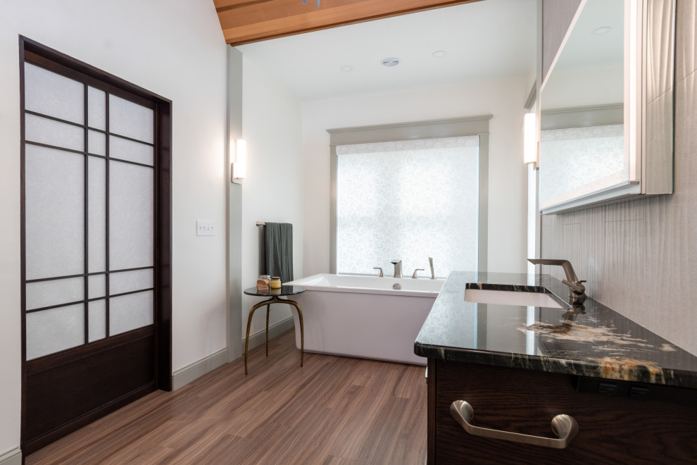 Large asian master bathroom in Boston with flat-panel cabinets, dark wood cabinets, a freestanding tub, a double shower, a one-piece toilet, beige tile, porcelain tile, white walls, medium hardwood floors, an undermount sink, granite benchtops, brown floor, a sliding shower screen, black benchtops, a single vanity and a floating vanity.