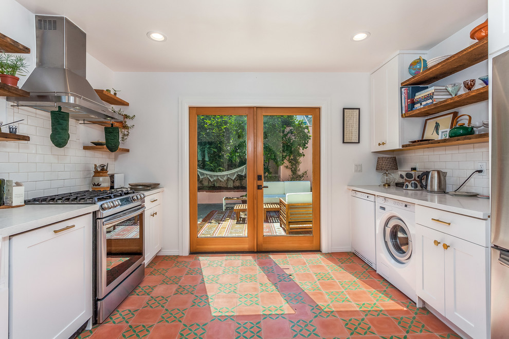 Inspiration for a mid-sized traditional galley separate kitchen in Los Angeles with a farmhouse sink, shaker cabinets, white cabinets, quartz benchtops, white splashback, subway tile splashback, stainless steel appliances, cement tiles, red floor and white benchtop.