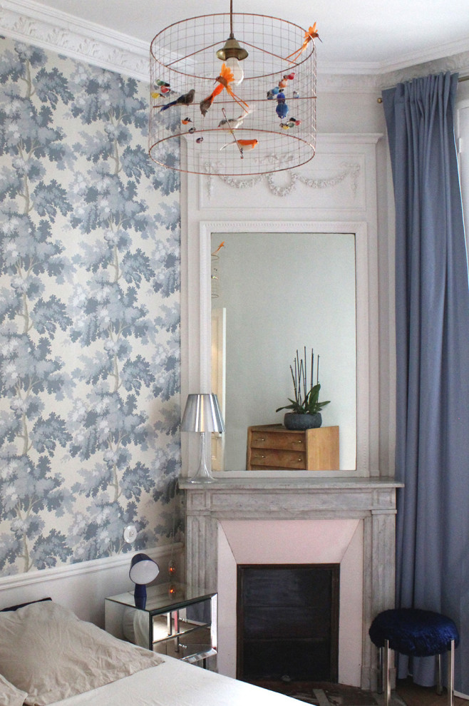 This is an example of a medium sized traditional master bedroom in Paris with blue walls, light hardwood flooring, a standard fireplace, a tiled fireplace surround and wallpapered walls.