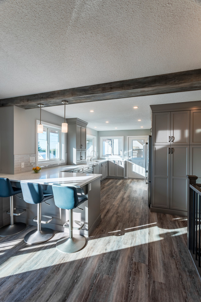 Large traditional u-shaped open plan kitchen in Vancouver with an undermount sink, shaker cabinets, grey cabinets, quartz benchtops, multi-coloured splashback, subway tile splashback, stainless steel appliances, laminate floors, a peninsula, multi-coloured floor and multi-coloured benchtop.