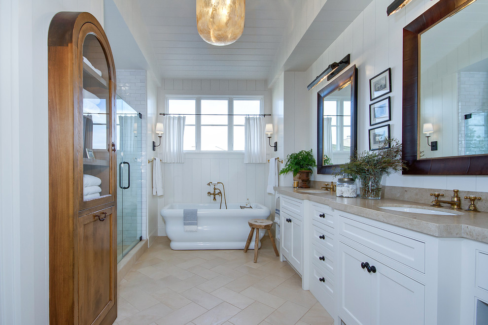 Design ideas for a large country master bathroom in Orange County with shaker cabinets, white cabinets, a freestanding tub, an alcove shower, a two-piece toilet, white tile, subway tile, white walls, travertine floors, an undermount sink, quartzite benchtops, beige floor, a hinged shower door and beige benchtops.